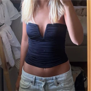 Svart tubtopp från Stradivarius - Snygg svart tubtopp från Stradivarius med rynkade detaljer, scrunch i midjan och en djup v-ringning. Endast använd 1 gång. Storlek M men passar även S och L då den är väldigt stretchig