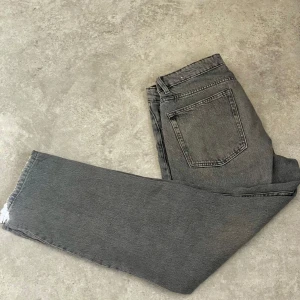Grå jeans från Zara - Snygga grå jeans från Zara med klassisk femficksdesign. De har en rak passform och är tillverkade i ett slitstarkt denimtyg. Perfekta för en stilren look.