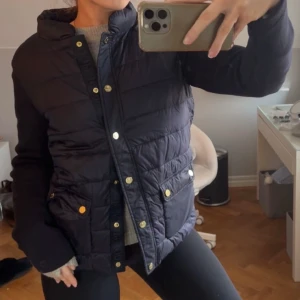 Mörkblå cardigan jacka från Joop! - Snygg mörkblå cardigan jacka från Joop! med guldknappar. Jackan har långa ärmar och två fickor framtill. Perfekt vårjacka och otroligt sparsamt använd står ingen storlek men jag skulle gissa på S/M