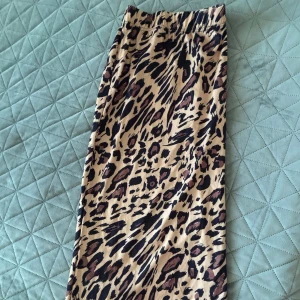 Leopardmönstrad kjol - Snygg leopardmönstrad kjol med elastisk midja. Perfekt för att ge en vild touch till din outfit. Kjolen har en bekväm passform och är lätt att matcha med olika toppar.