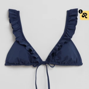 Mörkblå bikiniöverdel med volang - Snygg mörkblå bikiniöverdel med volangdetaljer längs kanterna. Aldrig använd med prislapp kvar. Säljer då den inte passar mig💕