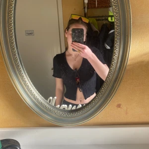 Svart ribbad bolerotopp - Säljer en svart ribbad bolerotopp med korta ärmar och knytning framtill. Perfekt för en trendig look. Det är mer som en kortärmad kofta. Så kan man ha ett vitt linne under och knyta😍