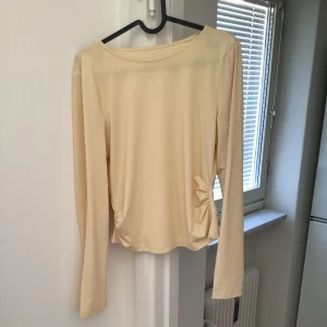 Gul långärmad topp - Säljer en stilren beige långärmad topp med rund hals. Perfekt för en enkel och elegant look. Passar bra till både jeans och kjol. Hör av dig vid intresse!