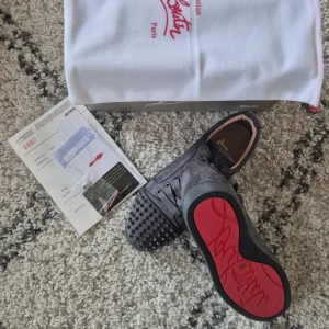 Grå loubs med spikar, fri frakt - Säljer ett par stiliga gråa loubs med spikar i storlek 43 med den ikoniska röda sulan. Dem är tillverkade i mocka vilket ger en najs känsla. Storlek 43. Fri frakt! 