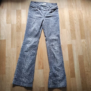 Leopardmönstrade bootcut jeans från Nelly - Snygga leopardmönstrade bootcut jeans från Nelly. Dessa jeans har en låg midja och är perfekta för att ge en trendig touch till din outfit. De har en klassisk femficksdesign och stängs med två knappar framtill.