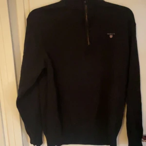 Svart half zip från gant  - Säljer en stilren svart tröja från GANT med dragkedja vid halsen. Tröjan har långa ärmar och en diskret logga på bröstet. Perfekt för en avslappnad och snygg look.