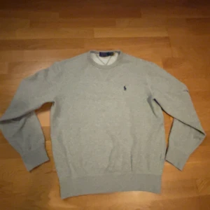 Grå tröja från Polo Ralph Lauren - Säljer en stilren grå tröja från Polo Ralph Lauren. Tröjan har en klassisk design med rund hals och långa ärmar. Storlek S i vuxen storlek.