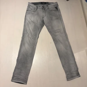 Gråa Replay jenas w31  - Snygga grå jean från Replay, modell Anbass med slim fit. Byxorna har en klassisk femficksdesign och en knappgylf. Perfekta för en stilren look. W31 och prisen är inte hugget i sten 