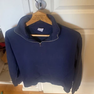 Mörkblå tröja med dragkedja från Zara - Säljer en mörkblå tröja från Zara med dragkedja vid halsen. Tröjan har långa ärmar och en enkel, stilren design. Perfekt för en avslappnad look.