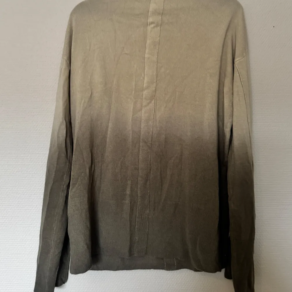 Säljer en stilren grön/till mörkare brun tröja från NA-KD med v-ringning och långa ärmar. Perfekt för lager-på-lager-stil. Tröjan har en mjuk och bekväm passform.. Neuletakit & Villapaidat.