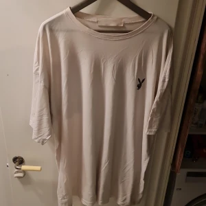 Vit t-shirt från Missguided med Playboy-tryck - Säljer en vit t-shirt från Missguided med stort Playboy-tryck på baksidan och en liten logga på framsidan. T-shirten har en avslappnad passform och är perfekt för en casual look.
