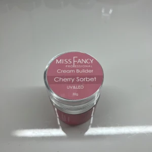 Miss Fancy Cream Builder Cherry Sorbet - Miss Fancy Professional Cream Builder i färgen Cherry Sorbet. Denna UV & LED-kompatibla gel är perfekt för att bygga starka och hållbara naglar. Kommer i en burk om 30g med en härlig rosa nyans.