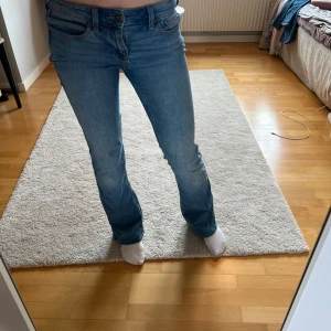 Blå jeans från Hollister - Säljer ett par blå low-rise bootcut jeans från Hollister. De har en klassisk femficksdesign och är tillverkade i mjukt stretchmaterial för extra komfort. Perfekta för en avslappnad stil.