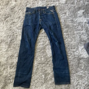 Blå jeans från Replay - Snygga blå jeans från Replay med klassisk femficksdesign och knappgylf. Jeansen har en rak passform och är tillverkade i slitstarkt denim. Perfekta för en avslappnad stil.
