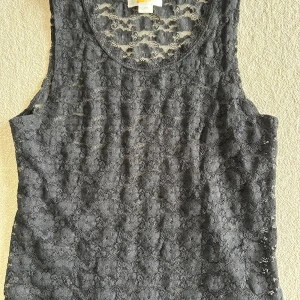 Svart spetslinne från Gina Tricot - Säljer ett snyggt svart spetslinne från Gina Tricot. Linnet är ärmlöst och har ett vackert spetsmönster som ger en elegant touch. Perfekt för att lägga till lite stil i din garderob.