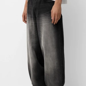 Svarta jeans med tvättad effekt- bershka - Snygga svarta jeans med en cool tvättad effekt som ger en vintage känsla. Byxorna har en loose passform och är perfekta för en avslappnad stil. De har klassiska fem fickor och knappgylf.