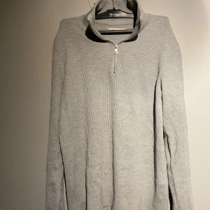 Grå stickad tröja från Jack and Jones - Säljer en stilren grå stickad tröja från Jack and Jones. Tröjan har en dragkedja vid halsen och långa ärmar. Perfekt för kyligare dagar och ger en avslappnad men snygg look.