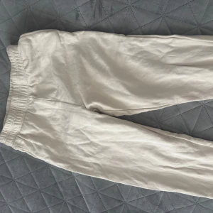 Beige byxor från Gina Tricot - Säljer ett par beige byxor från Gina Tricot med fickor. Byxorna har en elastisk midja för extra komfort och är tillverkade i ett mjukt material lite utsvängda vid benen. Perfekta för en avslappnad stil.