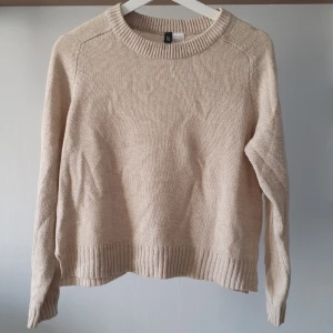 Beige stickad tröja från H&M Divided - Säljer en stilren beige stickad tröja från H&M Divided. Tröjan har en rund halsringning och långa ärmar med ribbade muddar vid ärmslut och nederkant. Bra skick men lite nopprig därav priset 💛