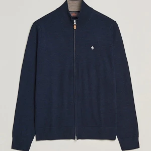 Mörkblå kofta med dragkedja - Snygg mörkblå kofta med dragkedja och liten broderad detalj på bröstet. Perfekt för kyligare dagar med sin stilrena design och långa ärmar. Passar både till vardags och mer uppklädda tillfällen.