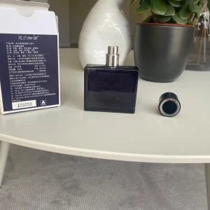 Blue De Flower of Story Eau de Toilette - Säljer en elegant Eau de Toilette från Flower of Story. Flaskan är fyrkantig och mörkblå med en silverfärgad spraypump. Förpackningen är också mörkblå med vit text. Perfekt för den som söker en sofistikerad doft. 100% full