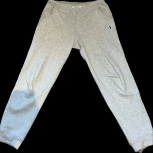 Grå mjukisbyxor från Ralph Lauren - Säljer ett par bekväma grå mjukisbyxor från Ralph Lauren. Byxorna har en elastisk midja med snörning och sidofickor. Perfekta för en avslappnad stil.