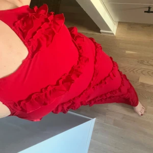 Röd långklänning med volanger - Säljer en fantastisk röd långklänning med volanger. Klänningen har smala axelband och en elegant passform som framhäver figuren. Perfekt för festliga tillfällen eller nu inför balen. Aldrig använd.