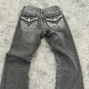 Gråa jeans - Ett par mörkgråa jeans med detaljer på fickorna, är från Gina young i storlek 164