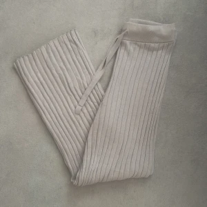 Beige ribbade byxor  - Snygga beige ribbade byxor med snörning. I jätteskönt material, är i storlek S. Använda få gånger så i jättefint skick. Byxorna är utsvängda längs ner. 