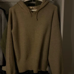 Beige stickad hoodie - Mysig beige stickad hoodie med huva och långa ärmar. Perfekt för kyliga dagar och enkel att matcha med olika outfits. Ribbstickade muddar vid ärmslut och nederkant ger en snygg detalj.