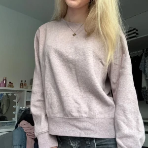 Ljusrosa sweatshirt - En basic ljusrosa sweatshirt med rund halsringning och långa ärmar. Tröjan har en avslappnad passform och är tillverkad i mjukt bomullsmaterial. Perfekt för en chill och enkel stil. 