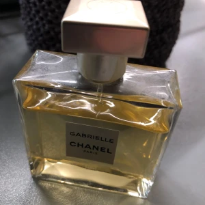 Gabrielle parfym från Chanel - Exklusiv parfym från Chanel, Gabrielle Paris. Flaskan är rektangulär i genomskinligt glas med en ljusgul vätska och har en elegant fyrkantig lock i silver. Perfekt för dig som gillar lyxiga dofter.