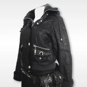 Black jacket with fur hood  - Säljer en svart jacka med fuskpälsdetaljer på krage och ärmslut. Jackan har flera silvriga dragkedjor, knappar och ribbade muddar. Snygg och edgy stil med markerad midja och coola detaljer.