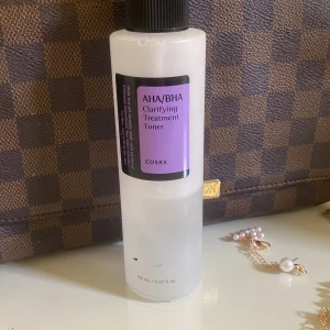 AHA/BHA Clarifying Treatment Toner från COSRX - En ansiktstoner från COSRX med AHA och BHA som hjälper till att exfoliera och fräscha upp huden. Kommer i en genomskinlig plastflaska med svart kork och lila etikett. Innehåller 150 ml.
