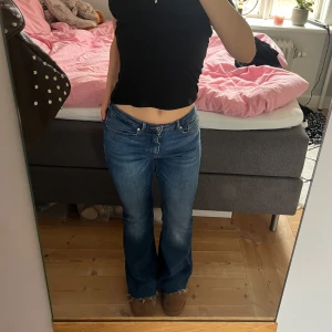 Blå bootcut jeans - Säljer ett par blå bootcut jeans med låg midja. Jeansen har klassisk femficksdesign och lätt utsvängda ben. Perfekta för dig som gillar en retroinspirerad look. Passar till många olika stilar. Storlek S och längd 30