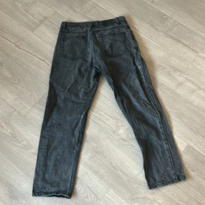 Grå jeansbyxor från Crunt - Säljer ett par grå jeansbyxor från Crunt med klassisk femficksdesign och raka ben. Byxorna har normal passform och stängs med dragkedja och knapp. Men har också ett litet lagat hål som man ser på bilden men inget som stör eller syns.