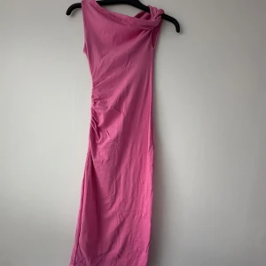 Rosa one shoulder långklänning från Stradivarius - Säljer en snygg rosa långklänning från Stradivarius med one shoulder-design. Klänningen har en smickrande passform och är perfekt för dig som vill sticka ut. Tillverkad i mjukt material som känns skönt mot huden. Köpt för 599