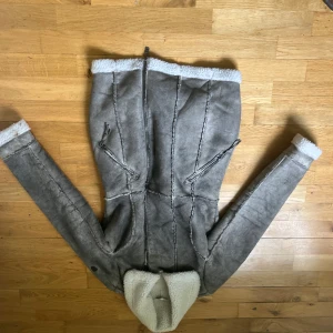 Grå fårskinnsjacka från Gipsy - Säljer en grå fårskinnsjacka från Gipsy med vit teddyfoder. Jackan har dragkedja framtill, två snedställda fickor med dragkedja och bred krage. Perfekt för kyliga dagar och har en klassisk, tidlös look.