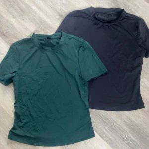Två basic tränings t-shirts  - Säljer två enkla t-shirts i storlek XS. En är svart och en är mörkgrön, båda med rund hals och korta ärmar. Materialet känns mjukt och stretchigt