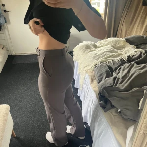 Grå kostymbyxor med raka ben - Snygga grå kostymbyxor med normal passform och raka ben. Byxorna har hög midja, diskreta fickor i sidorna och stängs med dragkedja och knapp framtill. Perfekta för en stilren look.