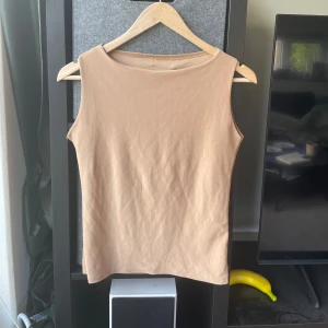 Beige ärmlös linnetopp Humana - Säljer en enkel och stilren beige ärmlös topp! Hål vid kragen och sönder vid ärmen