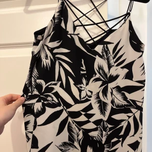 Svartvit blommig topp   - Snygg svartvit topp från Express med blommigt mönster. Den har smala axelband och en unik ryggdesign med korsade band. Passar XS