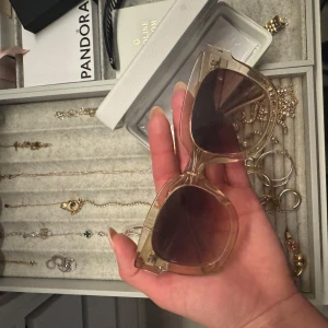 Beige transparenta solglasögon från CHIMI - Snygga solglasögon från CHIMI med transparent beige båge och bruna tonade glas. Cat-eye form som ger en trendig look. Perfekt accessoar för att lyfta din stil. Kommer med originaletui. 08or i en beige färg, superfina nu till sommaren