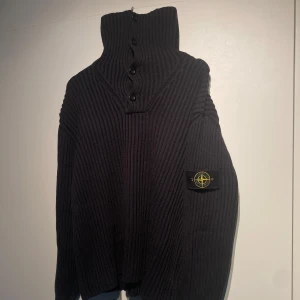 Stone Island Stickad Svart Tröja  - Stone Island grovstickad tröja med hög krage och knappar framtill. Varm & bekväm. Kvalitativ och lyxig. Nypris 5400kr. Sparsamt använd och i fint skick. Storlek M och sitter lite oversized. Fler bilder kan fås i DM! 