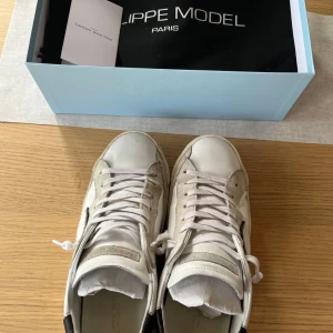 Vita sneakers från Philippe Model - Säljer ett par vita Philippe Model sneakers med svarta detaljer på hälen och klassisk snörning. Skorna har en rund tå och är tillverkade i skinn. Perfekta för dig som gillar stilrena och tidlösa sneakers. Skick 8/10. Nypris: 3900kr. Pris går att diskutera och skriv gärna vid frågor🤩