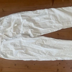 Vita linnebyxor från Zara - Säljer ett par vita byxor från Zara med resår i midjan och dragsko. Byxorna har raka ben och fickor bak. Perfekta för en avslappnad och stilren look.