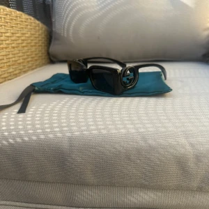 Svarta solglasögon med dekorativa bågar - Snygga svarta solglasögon med rektangulära linser och unika, dekorativa bågar. Perfekta för att ge en stilren touch till din outfit. 