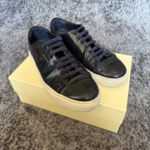 Axel Arigaro marinblå Cap-toe skor - Snygga marinblå sneakers från Axel Arigato med vit sula och matchande blå snören. Perfekta för en stilren look. Skorna kommer med originalförpackning och dustbag. Nypris är 1800kr.