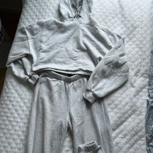 Grå croppad hoodie + matchande mjukis byxor  - Säljer en grå croppad hoodie med långa ärmar och en bekväm passform, du får även matchande mjukis byxor. Perfekt för en avslappnad stil. Hoodien har en klassisk design med en huva och ribbade muddar.