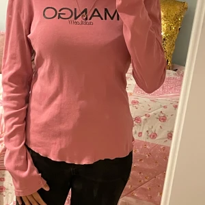 Rosa långärmad tröja från MANGO - Säljer en rosa långärmad tröja från MANGO med svart tryck på bröstet där det står 'MANGO addict!!!'. Tröjan har en rund halsringning och är tillverkad i mjuk bomull. Perfekt för en avslappnad och stilren look.